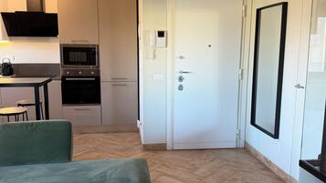 Apartamento moderno com cozinha compacta, área de jantar, sofá e um espelho grande.