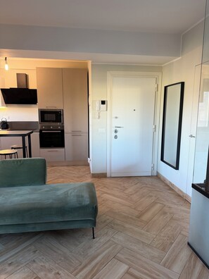 Apartamento moderno com cozinha compacta, área de jantar, sofá e um espelho grande.