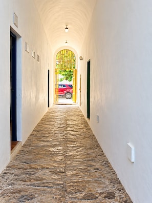 A corridor with stone flooring, white walls, and doors on either side. - Hotel Canela (Punta Cana)