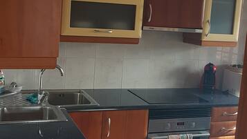 A kitchen with wooden cabinets, a stainless steel sink, and a built-in oven.