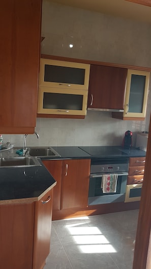 A kitchen with wooden cabinets, a stainless steel sink, and a built-in oven. - Holiday Home 'La Rectoria Vella' with Private Terrace, Wi-Fi and Air Conditioning (Sant Martí Sesgueioles)