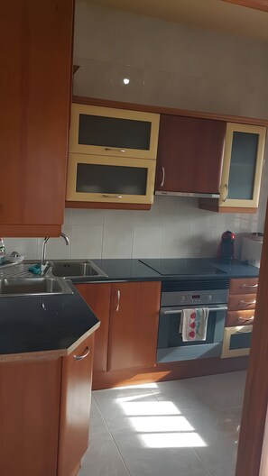 Una cocina con armarios de madera, un lavamanos de acero inoxidable y un horno empotrado.