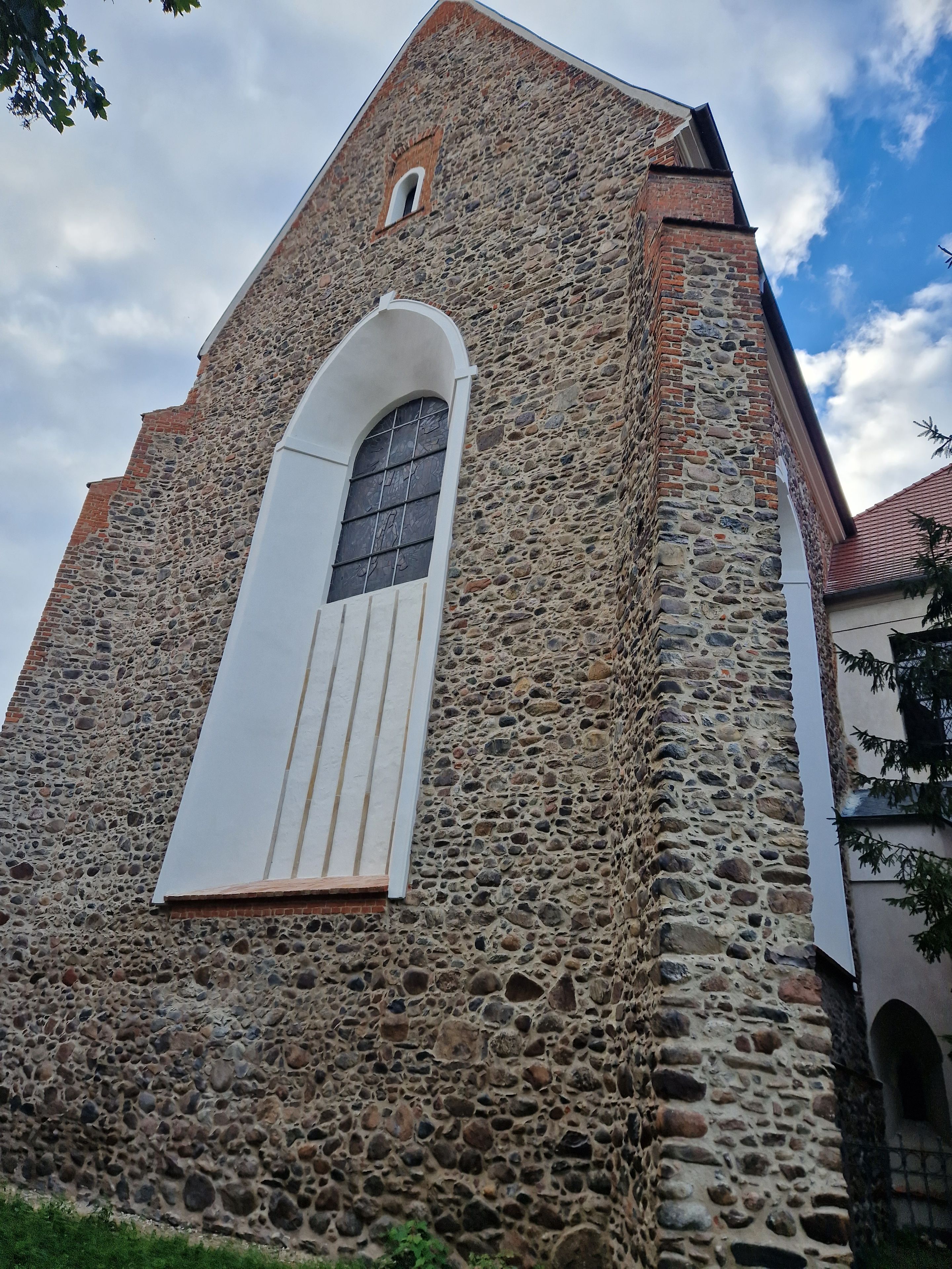 Un edificio de piedra con un amplio ventanal de arco y una ventana más pequeña arriba.