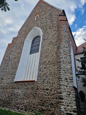 Ein Gebäude aus Stein mit einem großen Bogenfenster und einem darüber liegenden kleineren Fenster.