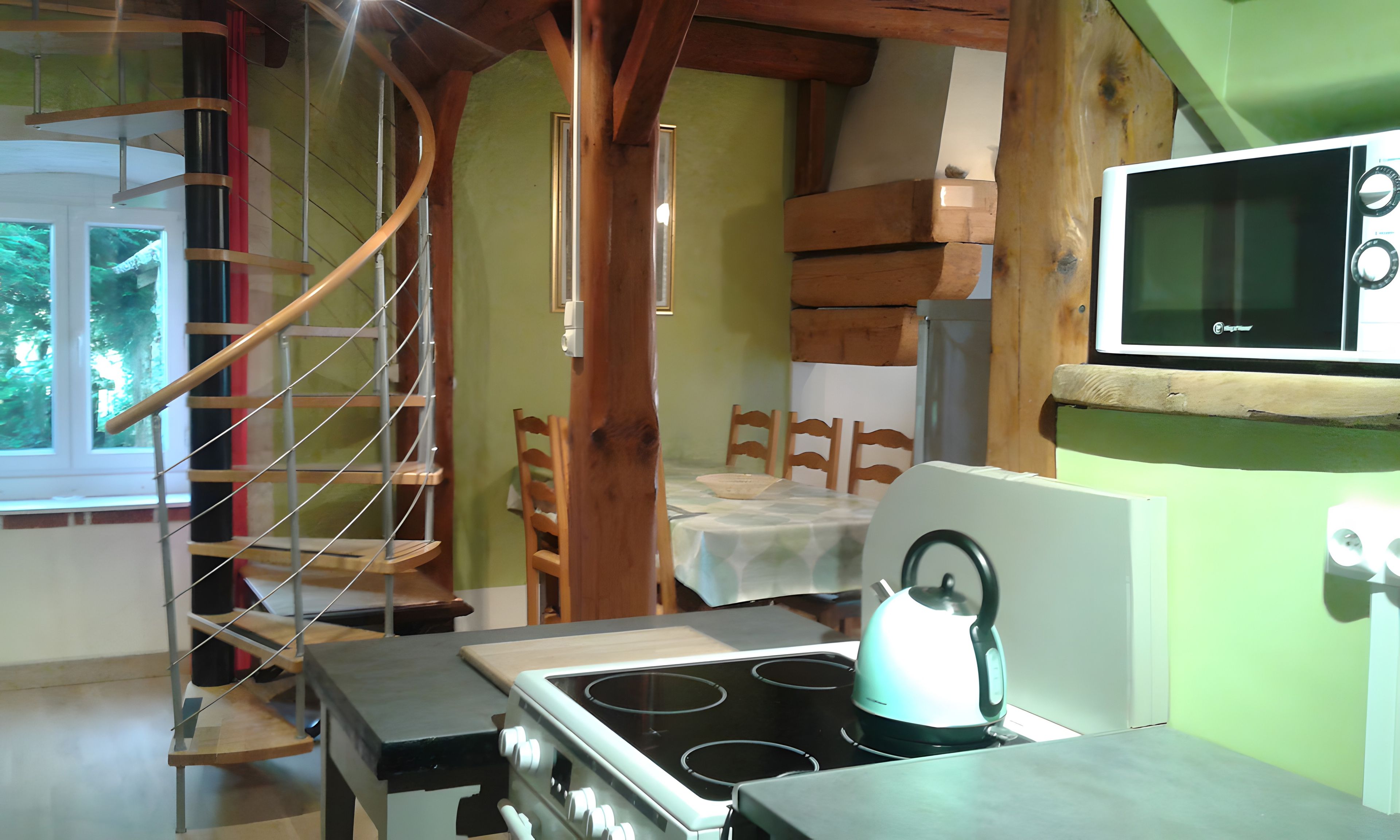 Une cuisine équipée d’une cuisinière, d’un four à micro-ondes et d’un escalier en bois.