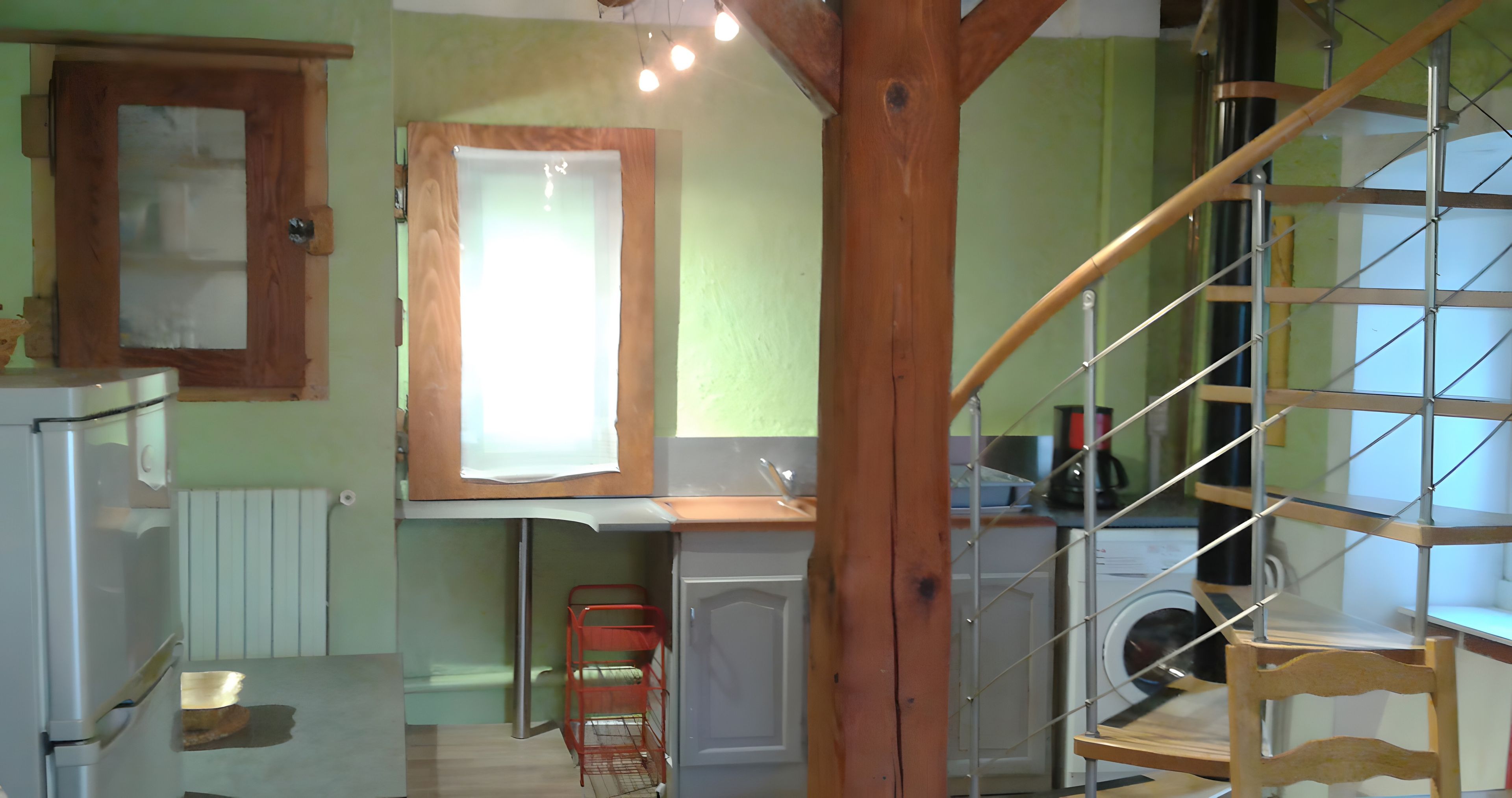 Une cuisine avec une fenêtre à cadre en bois, un lave-linge et une chaise rouge.