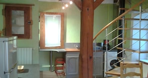 Une cuisine avec une fenêtre à cadre en bois, un lave-linge et une chaise rouge.