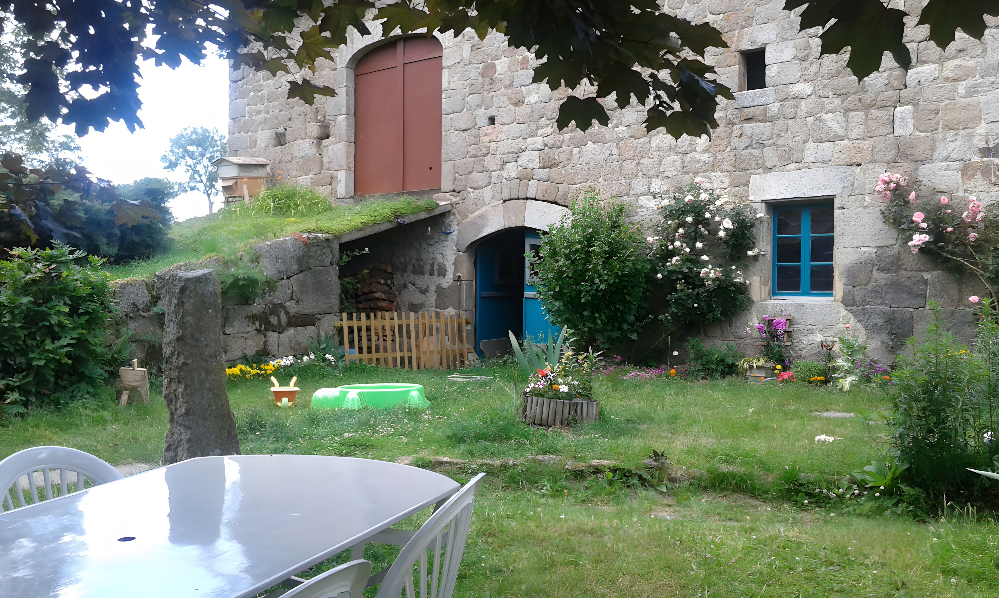 A stone building with a wooden door and a window with blue shutters.