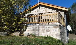 A stone building with a wooden balcony, surrounded by trees and rocks. - Cottage 'Le Petit Moulin' (Chenereilles)