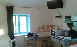 A compact kitchen with a window, a microwave, a kettle, and a small sink. - Cottage 'Le Petit Moulin' (Chenereilles)