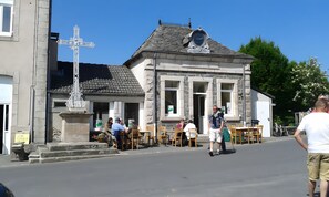 A building with a stone facade, a cross, and outdoor seating. - Cottage 'Le Petit Moulin' (Chenereilles)