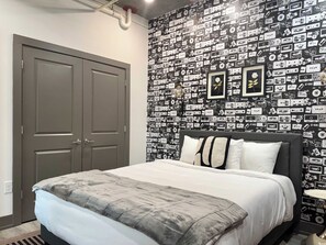 A bedroom with a bed, a wardrobe, and a wall covered with cassette tapes. - Industrial Loft Steps to Mercedes-Benz Stadium (Atlanta)