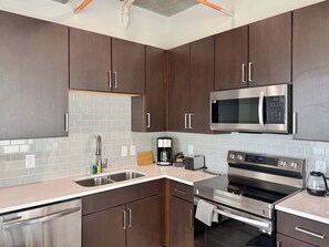 Una cucina moderna con elettrodomestici in acciaio inossidabile, un lavello doppio e pensili in legno.