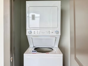 Eine Waschmaschine mit Frontöffnung, einer Bedienblende, einer Tür und einem kleinen Ablagebrett.