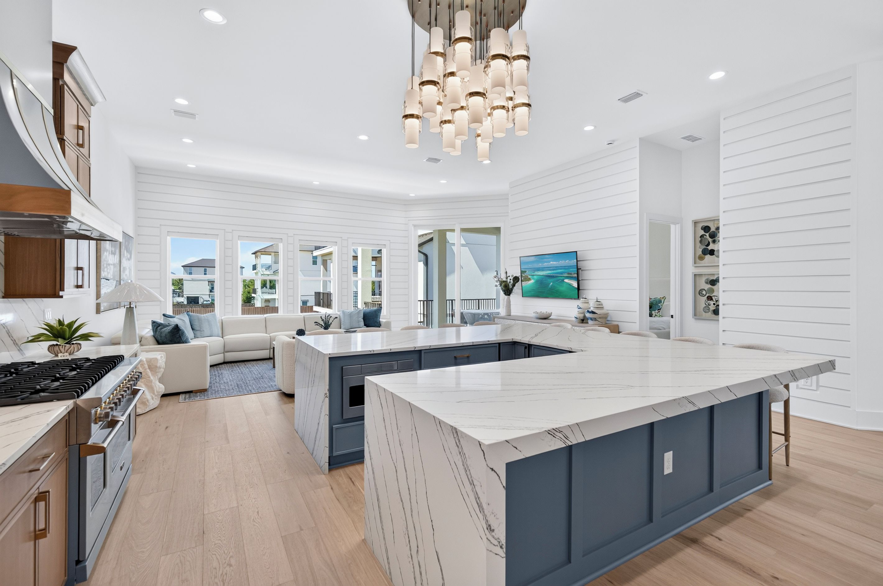 A modern kitchen with a large island, built-in appliances, and a view of the neighborhood.