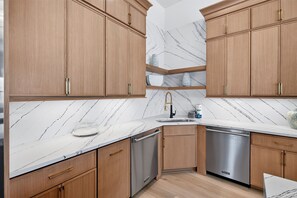 A modern kitchen with wooden cabinets, a marble countertop, and stainless steel appliances. - Good Tides: Private Beach, Heated Pool & Spa, Free Golf Cart, 5,700+ SqFt (Miramar Beach)