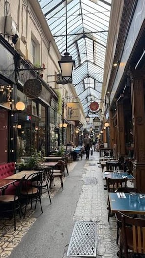 An indoor corridor with tables and chairs, a patterned floor, and a glass ceiling. - Parisian Luxury with Eiffel Tower Views & Designer Interiors (Paris)