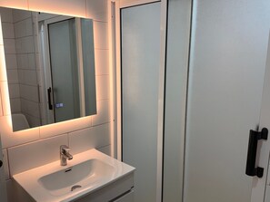 A bathroom with a white sink, a mirror, and a door.