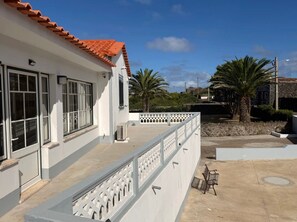 Een gebouw met een witte gevel, een dak met rode tegels en een balkon met een witte balustrade.
