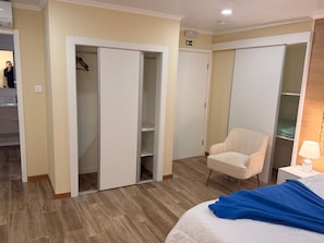 A hotel room with a bed, a chair, a nightstand, and a wardrobe.