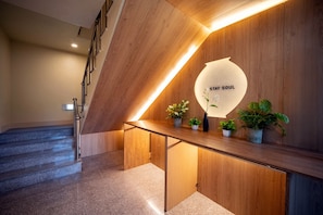 Un interior moderno con un mostrador de recepción de madera, una escalera y un letrero en la pared que dice 'STAY SOUL'.