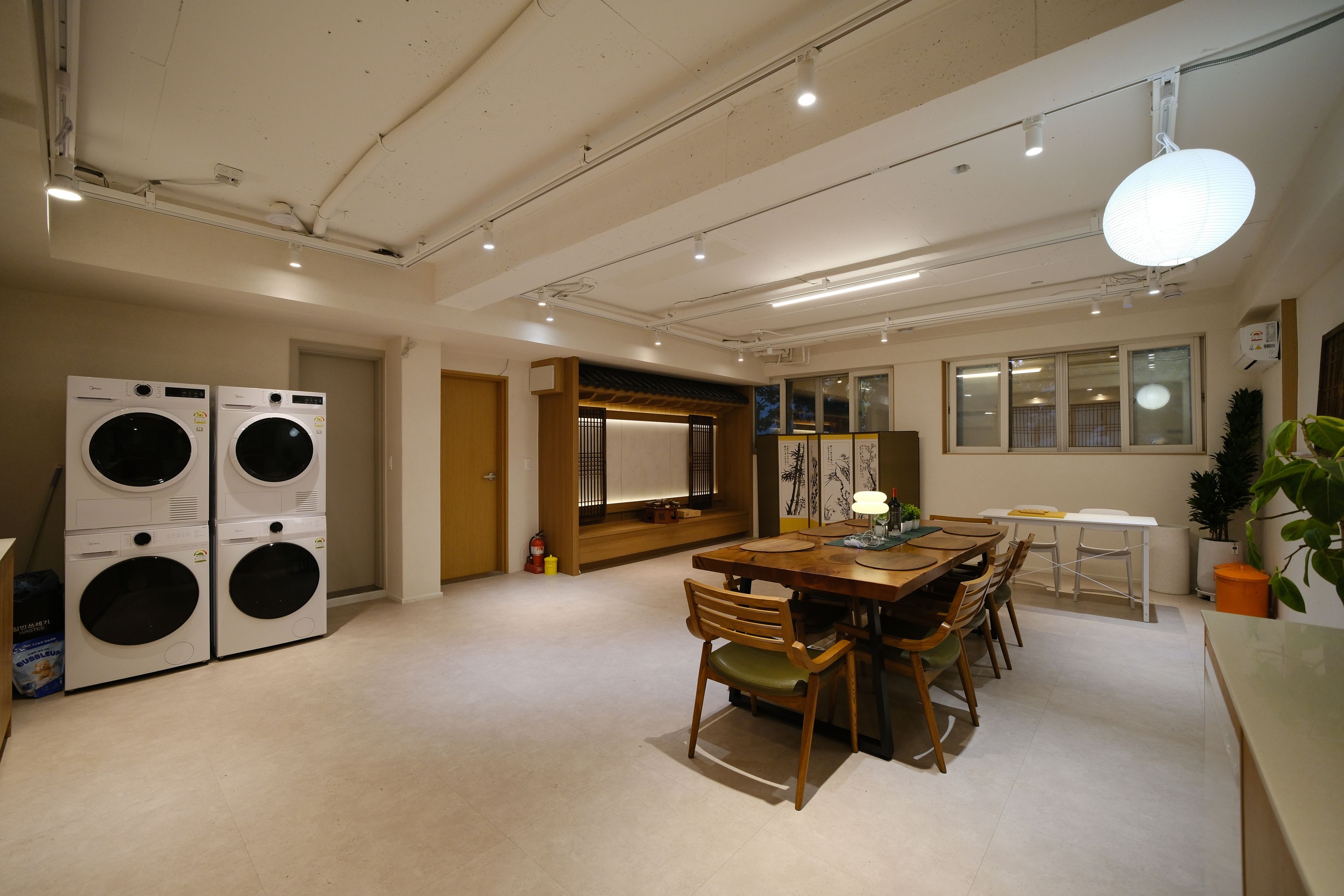 Una habitación amplia con zona de comedor, lavadora y una puerta corrediza tradicional japonesa.