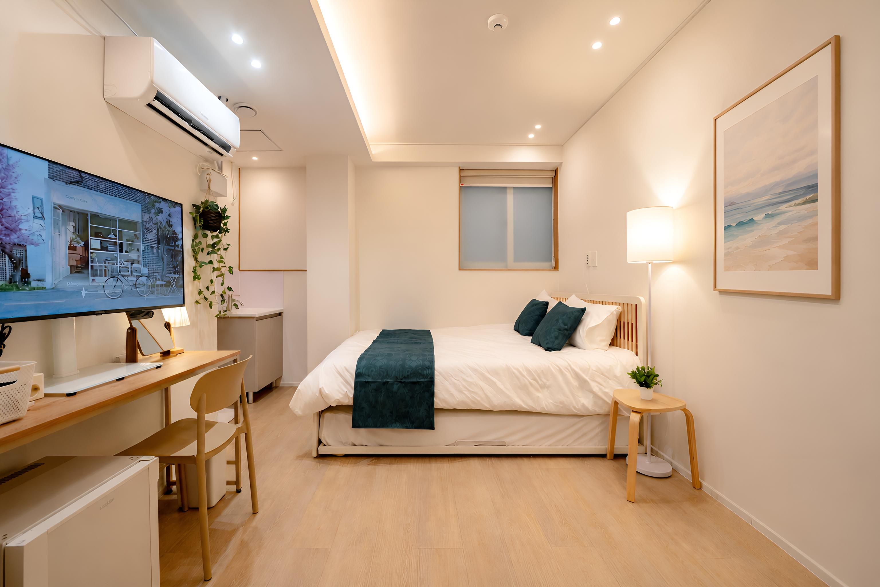 Une chambre moderne avec un lit, une table de chevet, une lampe et un bureau avec un ordinateur.