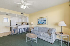 A compact living space with a kitchenette, a sofa, two small tables, and a ceiling fan. - ☀️Ocean Front Condo with Expansive Views-Daytona Ocean Walk Resort 706☀️ (Daytona Beach)