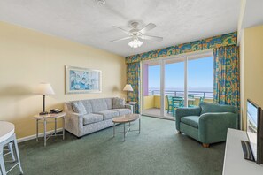 A hotel room with a sofa, armchairs, a small table, a ceiling fan, and a large window with a view. - ☀️Ocean Front Condo with Expansive Views-Daytona Ocean Walk Resort 706☀️ (Daytona Beach)