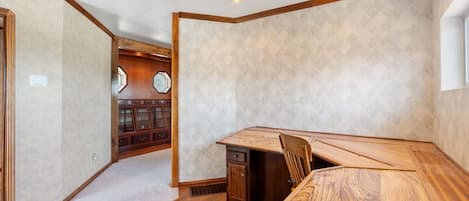 A room with a wooden dining table, a built-in cabinet, and a patterned wall.