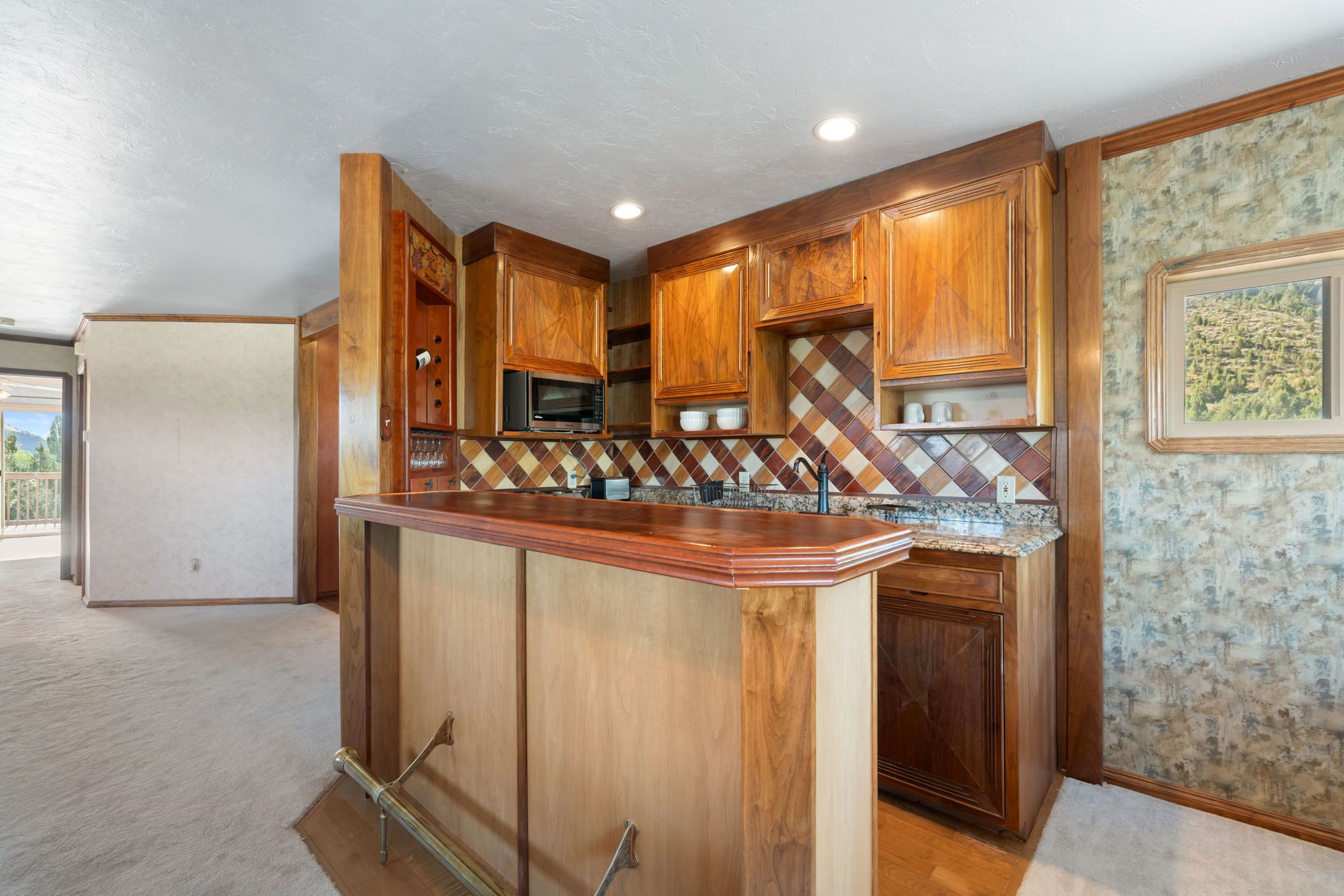 Cocina con armarios de madera, encimera de granito y salpicadero con diseño de rombos.