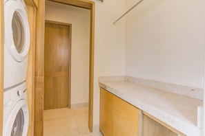 A laundry area with a washing machine, a dryer, and a wooden door leading to another room. - El Tigre Luxury Golf Villa w/ Pool & Beach Club (Nuevo Nayarit)