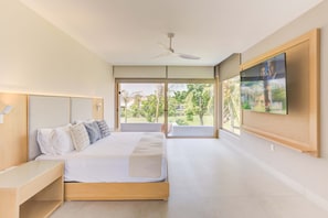 A modern bedroom with a large bed, a ceiling fan, and a view of a garden through glass doors. - El Tigre Luxury Golf Villa w/ Pool & Beach Club (Nuevo Nayarit)