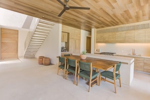 A modern kitchen with a central island, wooden ceiling, and a staircase. - El Tigre Luxury Golf Villa w/ Pool & Beach Club (Nuevo Nayarit)