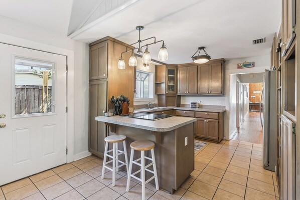A modern kitchen with a central island, bar stools, and pendant lighting.