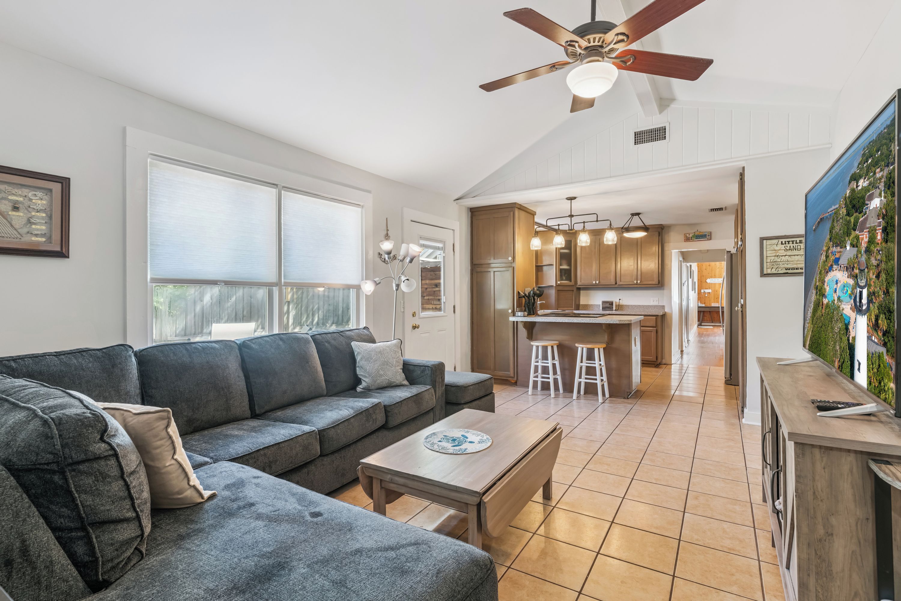 A modern living room with a grey sectional sofa, a wooden coffee table, and a ceiling fan.