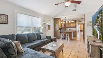 A modern living room with a grey sectional sofa, a wooden coffee table, and a ceiling fan.