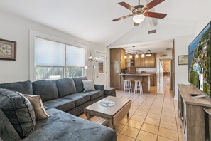 A modern living room with a grey sectional sofa, a wooden coffee table, and a ceiling fan.