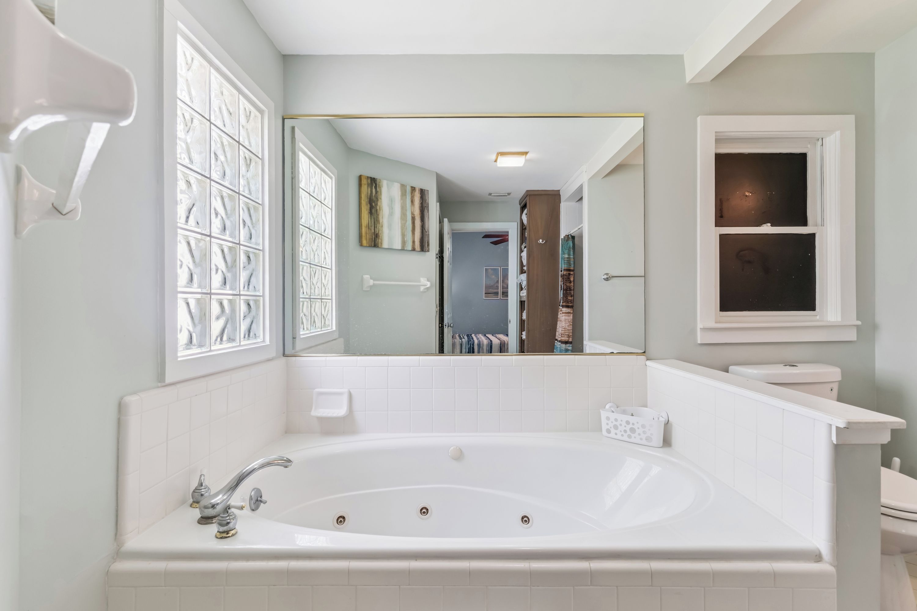 A bathroom with a large bathtub, a toilet, and a window with frosted glass.