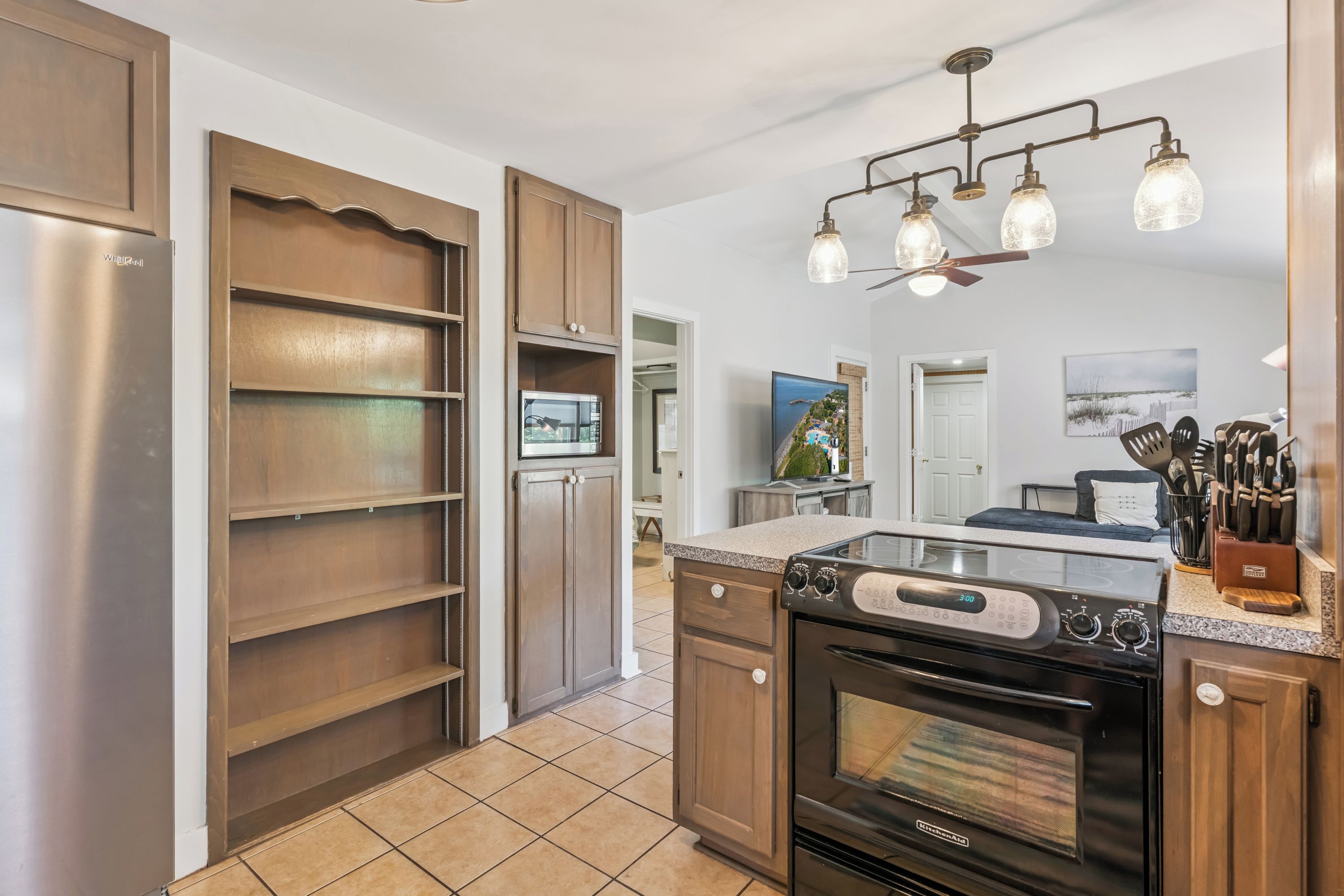 Una cocina moderna con horno empotrado, refrigerador y comedor con vista al mar.