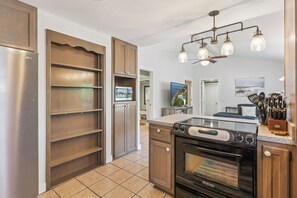 A modern kitchen with a built-in oven, a refrigerator, and a dining area with a view of the sea. - Barefoot Breeze Bungalow sleeps up to 11 guests (St Simons Island)