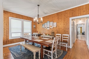 A dining area with a wooden table, chairs, and a chandelier. - Barefoot Breeze Bungalow sleeps up to 11 guests (St Simons Island)