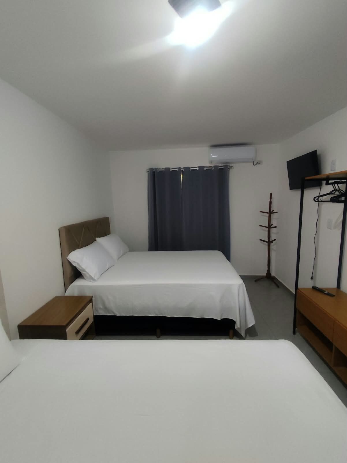 Una camera d'albergo con un letto, un comodino e una TV montata a parete.
