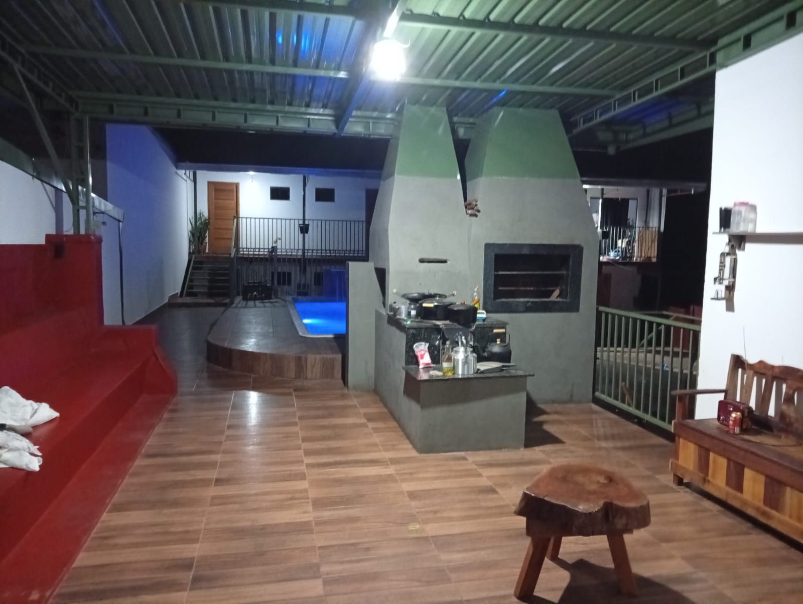 Un espacio interior con piscina, zona de cocina y sofá rojo.