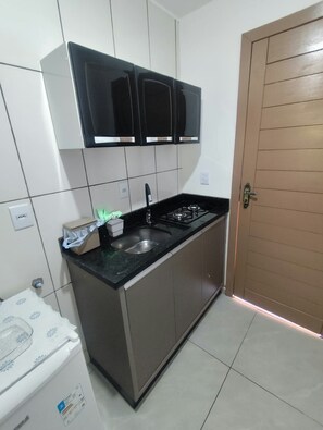 Una cucina compatta con un piano cottura a gas, un lavello e una porta in legno.