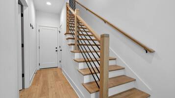 A staircase with wooden steps and a black handrail, leading to a white door at the top.