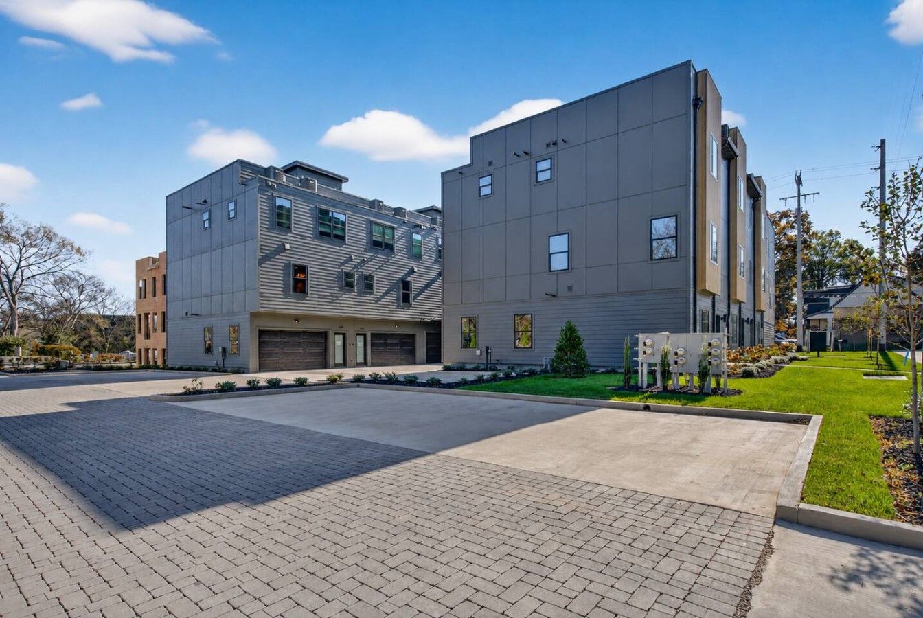 A modern building with a garage, paved driveway, and landscaped area.
