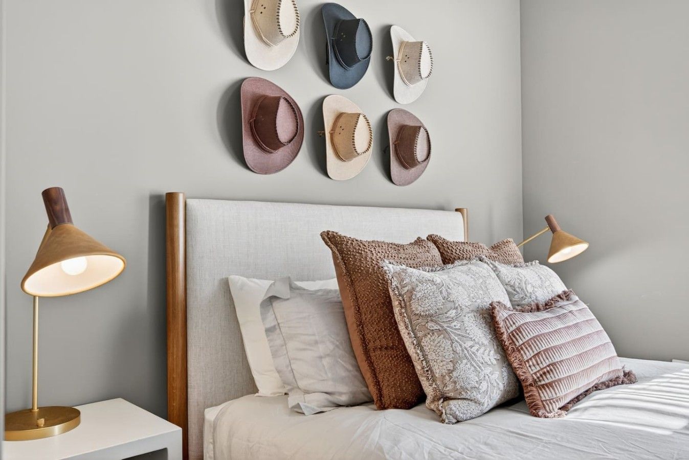 A bedroom with a bed, pillows, a nightstand, a lamp, and wall-mounted decorative items.