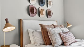 A bedroom with a bed, pillows, a nightstand, a lamp, and wall-mounted decorative items.
