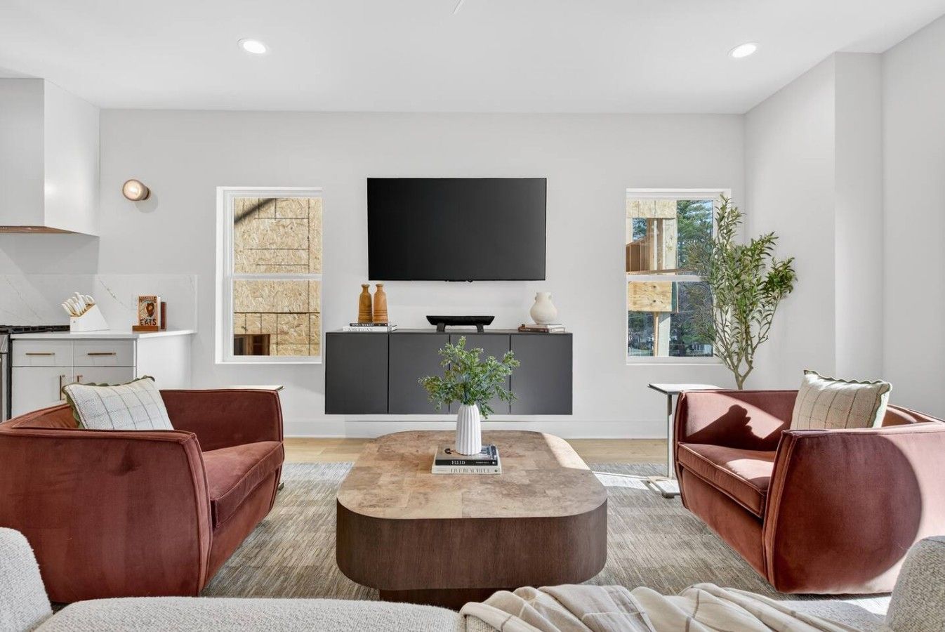 A modern living room with a flat-screen TV, two sofas, a coffee table, and a bookshelf.